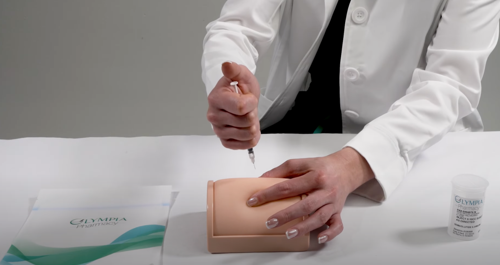 Healthcare professional injecting into a practice pad using a syringe, demonstrating injection technique.
